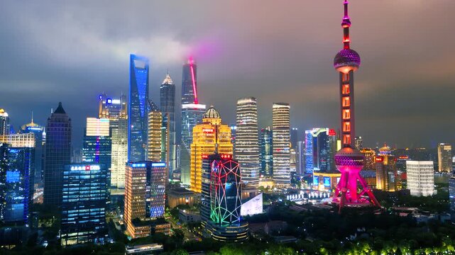 Aerial shot of the illuminated Lujiazui financial district skyline, including the Oriental Pearl Tower and modern skyscrapers, visible at night in Shanghai, China.