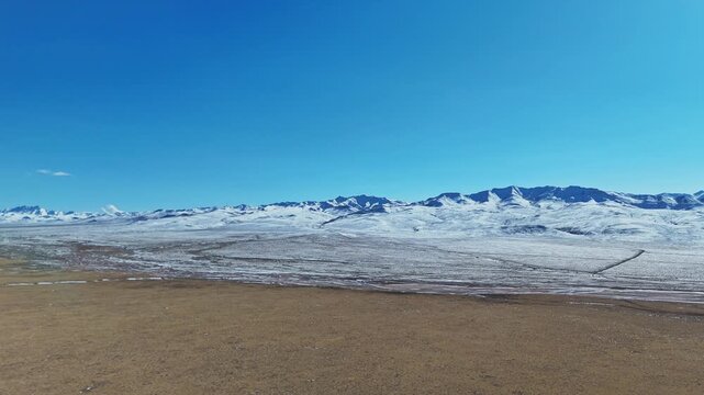 Qilian Grassland, Xining, Qinghai Province, China - A Vast, Snow-dusted Plain Stretches Toward Distant Mountain Ridges Beneath a Clear, Deep Blue Sky - Push In Shot