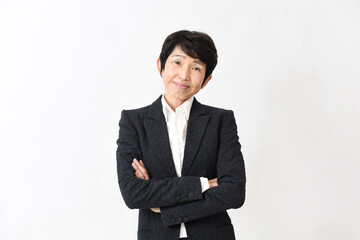 スーツ姿で腕組みをする笑顔の中高年のアジア人女性