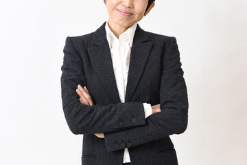 スーツ姿で腕組みをする笑顔の中高年のアジア人女性