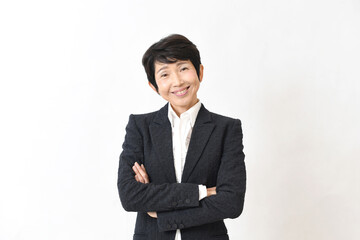 スーツ姿で腕組みをする笑顔の中高年のアジア人女性