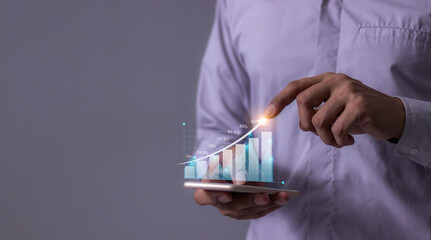 Young man with smartphone hand touching to visualize money growth The phone screen displays graphs and charts showing increasing investment and savings trends, along with an increased account balance