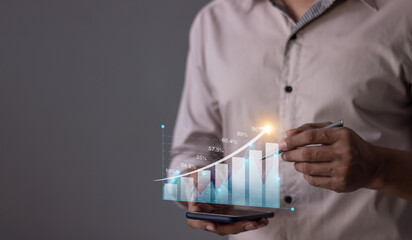 Young man with smartphone hand touching to visualize money growth The phone screen displays graphs and charts showing increasing investment and savings trends, along with an increased account balance