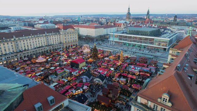 Amazing aerial view of dresden's historic striezelmarkt at dusk, bustling with crowds, glowing stalls, festive lights, a decorated tree and traditional holiday atmosphere