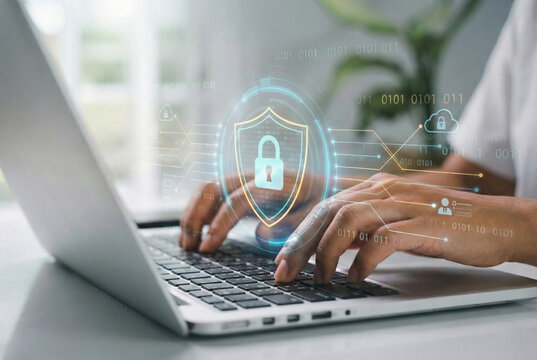 A businessman works on his laptop at home with a virtual display showing a symbol to signify cyber security privacy and online data protection - Powered by Adobe