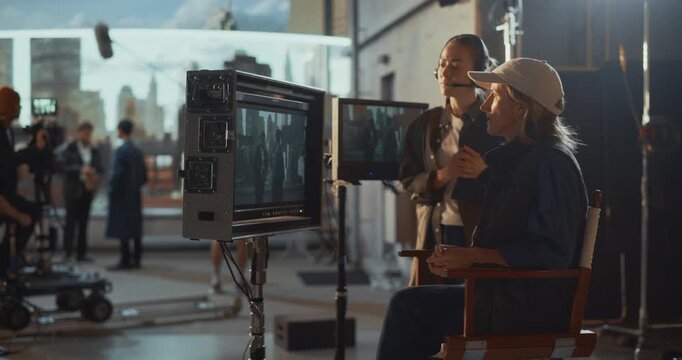 Female Director and Assistant Supervise an Rooftop Action Sequence From Video Monitors, Working on Script, Cinematography, Performers While Coordinating Precise Framing During Active Film Shooting