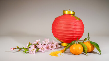 Celebrating spring with a vibrant red lantern, blooming flowers, and ripe oranges on a serene table setting