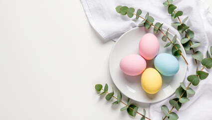 Colorful eggs artfully arranged on a plate surrounded by fresh eucalyptus leaves on a bright, clean surface