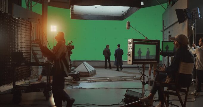 Behind the Scenes on a Busy Film Set, Director, Crew and Actors on a Collaborative Project. Shooting a Dramatic Dialogue Scene Against a Large Green Screen for Visual Special Effects