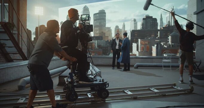 Camera Operator Rides a Dolly on Rooftop Movie Set, Actors Perform Great Dramatric Dialogue While Monitoring Framing on Monitor and Using Virtual Production, Cinematic Movement and Visual Aesthetics.