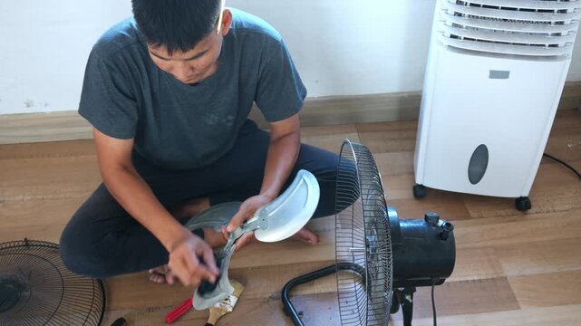 Focused man repair fan at home with care for comfortable