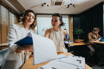 Obraz premium A group of professionals collaborates around a desk, reviewing reports, graphs, and notes during a corporate meeting.