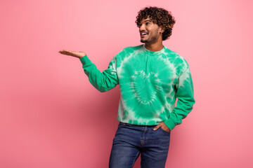 Young male model in green tie dye sweater poses with friendly gesture against pink background for lifestyle fashion stock image