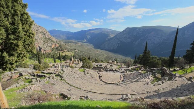Delphi temple 4k video. Panoramic view of the ancient Greek theater of Delphi built into the rocky mountainside, overlooking a deep green valley under a clear blue sky.