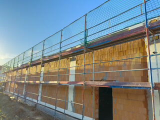 Fototapeta premium Construction site featuring scaffolding with a clear blue sky in the background, showcasing the building process of a new structure at sunset