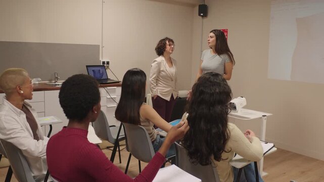 Female student presenting project in classroom with teacher and classmates