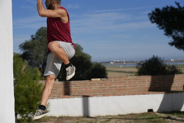 Man performing outdoor fitness training jumping on wall