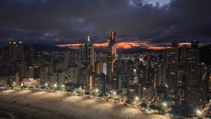 Fototapeta premium Aerial View of Balneario Camboriu Cityscape at Dusk with Illuminated Skyscrapers and Beach