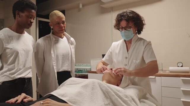 Esthetician training students in facial treatment techniques