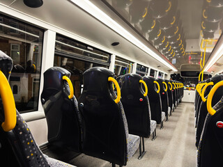 Interior of empty Manchester bus with yellow handrails and rows of seats at night