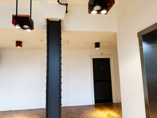 Naklejka premium Modern university interior with a large steel column, ceiling lights, doorway and wood floor in Manchester, UK
