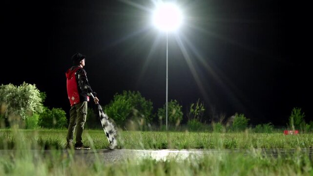 Night race marshal waving checkered flag under bright floodlight, blurred kart streaks past finish on wet