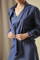 Female model wearing monochrome denim blue outfit. Midi skirt and bow-tie neck blouse. Fashion studio shot.