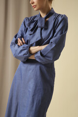 Female model wearing monochrome denim blue outfit. Midi skirt and bow-tie neck blouse. Fashion studio shot.