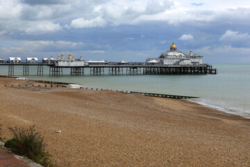 Fototapeta premium Photo with a view of the Eastbourne Pier, the beach and the English Channel against a stormy sky in Eastbourne, United Kingdom
