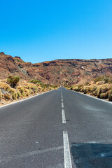 Tenerife - Long desert road to Teide through rocky hills under a clear blue sky