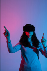 Young woman using VR headset with neon lighting gestures in immersive virtual reality environment