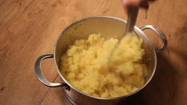 Homemade mashed potatoes using a potato masher in a pot 