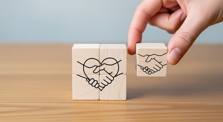 Hand placing wooden block with handshake symbol next to heart handshake