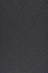 A full-frame, dark background featuring a subtly textured surface of black matte paper with faint diagonal lines and fibers