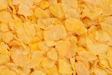 A bright, textured background of yellow and golden corn flakes fills the entire frame