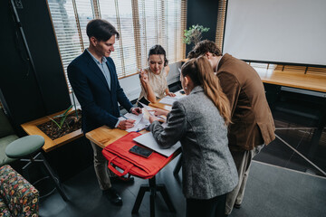 A diverse team gathers around a high table, reviewing papers and digital devices in a modern office space for a collaborative business meeting.
