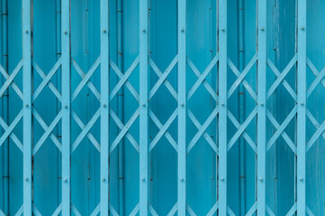 Blue expandable steel gate showing a traditional folding mechanism