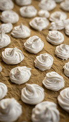 Soft-focus meringue drops arranged on crinkled baking paper, highlighting texture and artisan dessert preparation for food marketing.