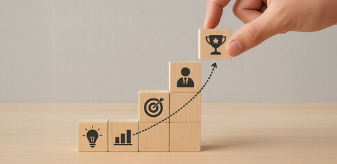 Hand Placing Trophy Icon on Wooden Blocks Staircase Representing Business Growth and Goal Achievement