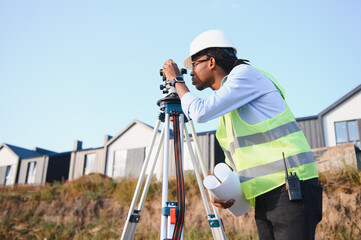 Naklejka premium African american surveyor working with theodolite on construction site