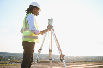 African american surveyor working with a theodolite on construction site