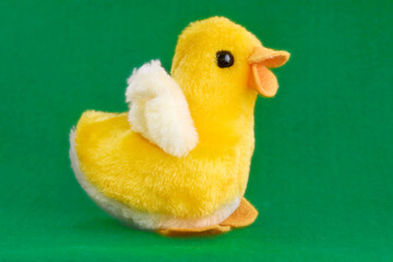 Adorable yellow plush chick toy with fluffy white wings, standing on a vibrant green background. A cheerful and cute companion for children, symbolizing innocence and springtime joy.