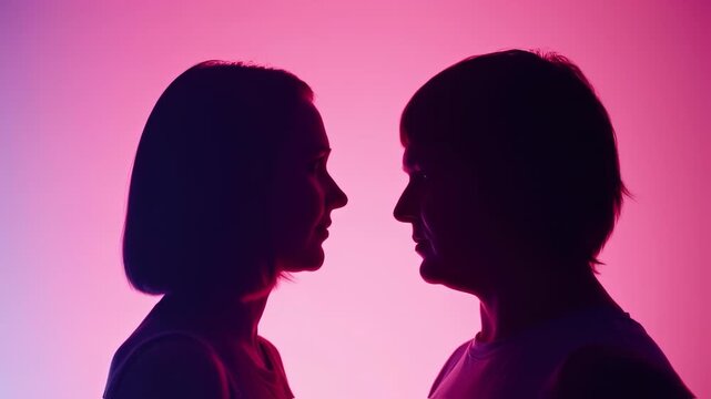 Silhouetted profiles of two people facing each other with a gradient pink/purple background