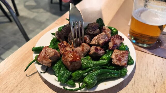 Cubes of entrecote with Padron pepper, a delicious Catalan dish. Tapas concept. High quality 4k footage