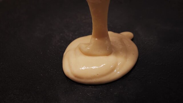 Fluffy pancake mix gradually rises in a cast iron skillet, revealing a golden texture. Cooking pancake at home. High quality 4k footage