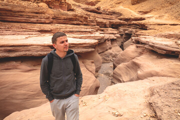 Dry river bed, wilderness. Desert natural landscape. Sandstone texture. Young man walking in Red Canyon in the Negev Desert near Eilat, Israel.