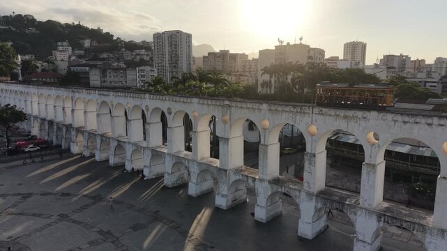 RIO DE JANEIRO, BRAZIL &ndash; NOVEMBER 2025: Aerial overhead shot of yellow tram riding on the top of Carioca Aqueduct (Arcos de Lapa), a famous landmark in old part of Rio de Janeiro, Brazil
