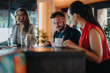A group of coworkers chats at a stylish cafe, sipping drinks while they converse. The scene conveys casual collaboration and friendly energy during a midday break.