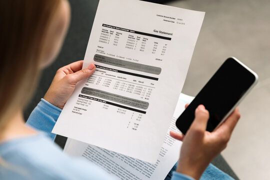 Using a smartphone to check a gas statement at home in the living room