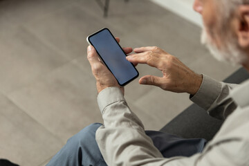 Older man uses smartphone at home for online banking and communication